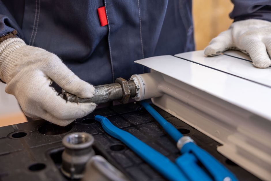 Plumber installing a radiator pipe with tools