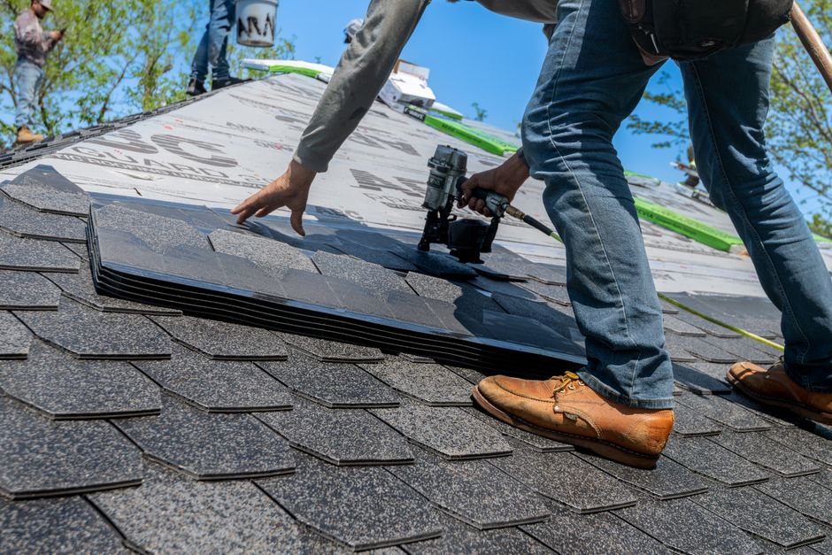 Roofer using a nail gun to install shingles